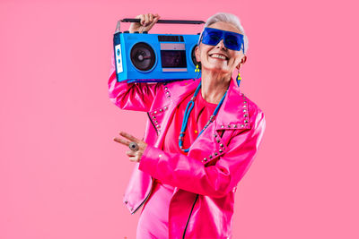Portrait of woman with camera against pink background