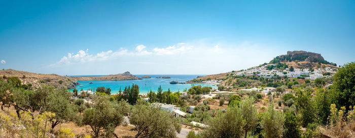 Panoramic view of sea and mountains against blue sky