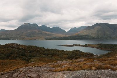 Scenic view of lake and mountains against cloudy sky
