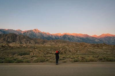 Rear view of man standing on mountain against clear sky