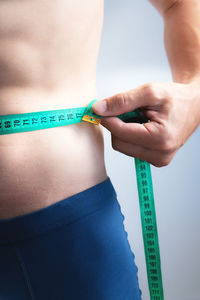 Midsection of woman holding tape measure