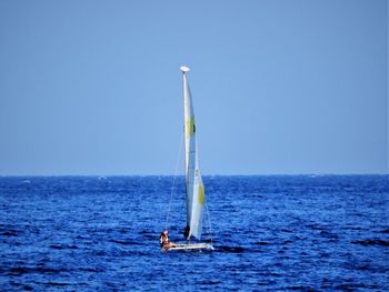 Sailboat in sea against clear blue sky