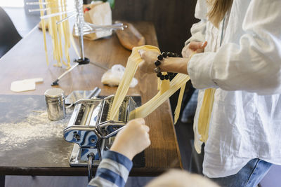 Woman preparing tagliatelle with dough in pasta maker