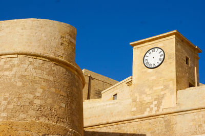 Low angle view of clock tower against clear blue sky