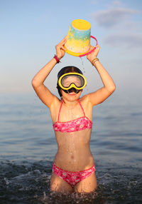 Low section of woman with arms raised against sea