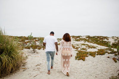 Mixed race couple holding hands walking on beach