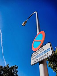 Low angle view of road sign against clear blue sky