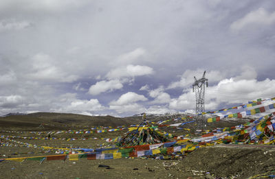 Colorful prayer flags hanging over landscape against cloudy sky