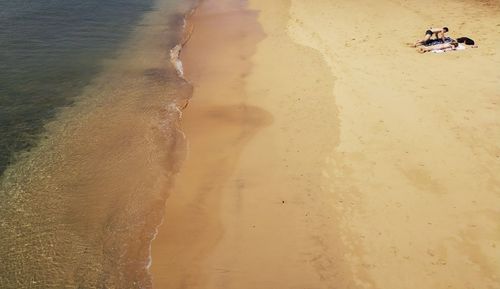 Overhead view of couple on deserted golden sandy beach and shoreline
