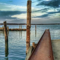 Wooden pier on sea against cloudy sky