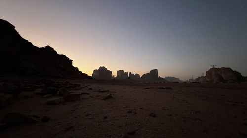 Rock formations on beach against sky during sunset