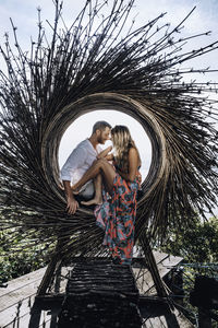 Couple kissing against trees and plants