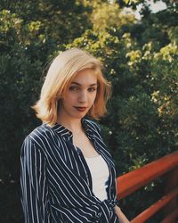 Portrait of young woman standing by railing