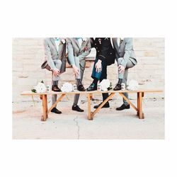 Low section of bridegroom with groomsmen standing on bench against wall