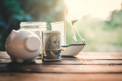 Close-up of rolled paper currency with piggy bank and toys on table