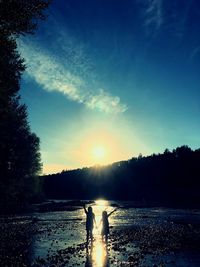 Silhouette people on land against sky during sunset