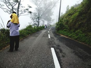 Rear view of grandfather carrying granddaughter on shoulder during foggy weather