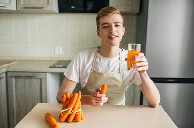 Portrait of smiling mid adult man holding drink at table