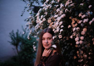 Portrait of a beautiful young woman standing by plants