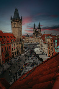 Clock tower amidst buildings in city at sunset