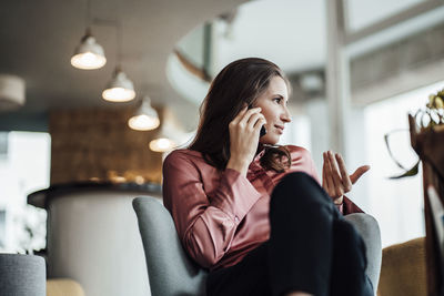 Young woman using mobile phone while sitting on sofa