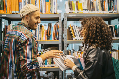 Man and woman discussing over book in library at community college