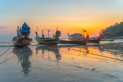 Boats moored on sea against sky during sunset