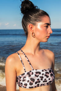 Portrait of beautiful young woman looking away at beach