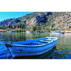 Boats moored on sea against clear blue sky