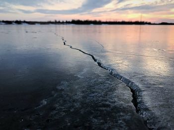 Close-up of frozen lake against sky during sunset