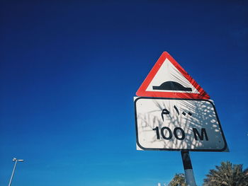 Low angle view of road sign against blue sky