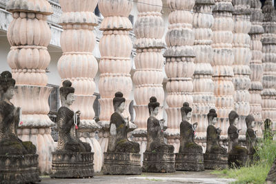 Old buddha statues in row by columns at temple
