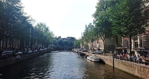 Boats in canal amidst city against sky