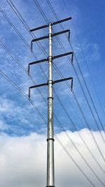 Low angle view of electricity pylon against blue sky
