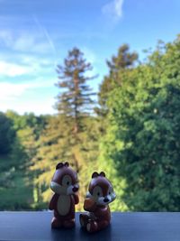 Close-up of stuffed toy by trees against sky