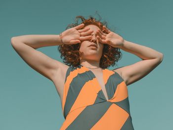 Low angle view of woman standing against clear blue sky