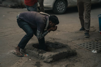 Man drinking water from a drain