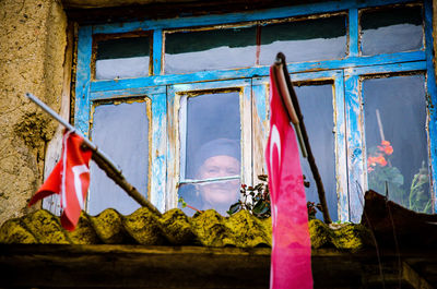 Low angle view of woman looking away seen through window of old building