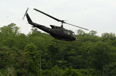 Helicopter flying by trees against clear sky