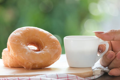 Close-up of hand holding coffee cup on table