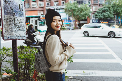 Young woman standing on road in city