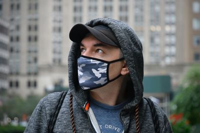 Portrait of young woman covering face outdoors