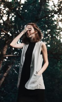 Beautiful young woman standing against tree