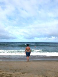 Rear view of friends on beach against sky