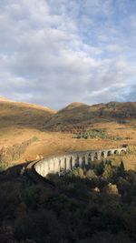 Arch bridge over landscape against sky
