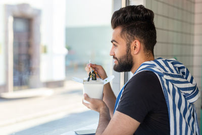 Side view of a young man drinking glass