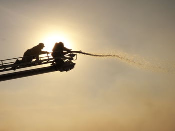 Low angle view of silhouette men against sky during sunset