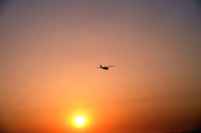 Airplane flying in sky during sunset
