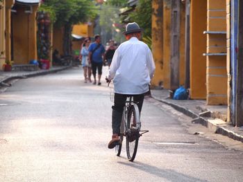 Rear view of man riding bicycle on city street