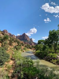 Scenic view of river by mountains against blue sky